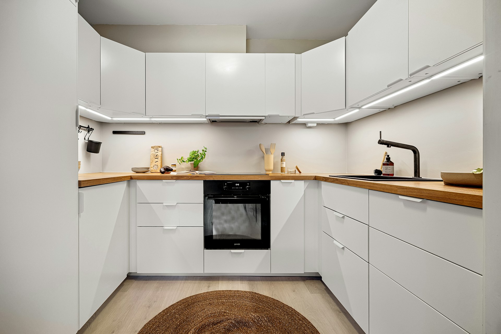 A kitchen with white cabinets and a brown rug